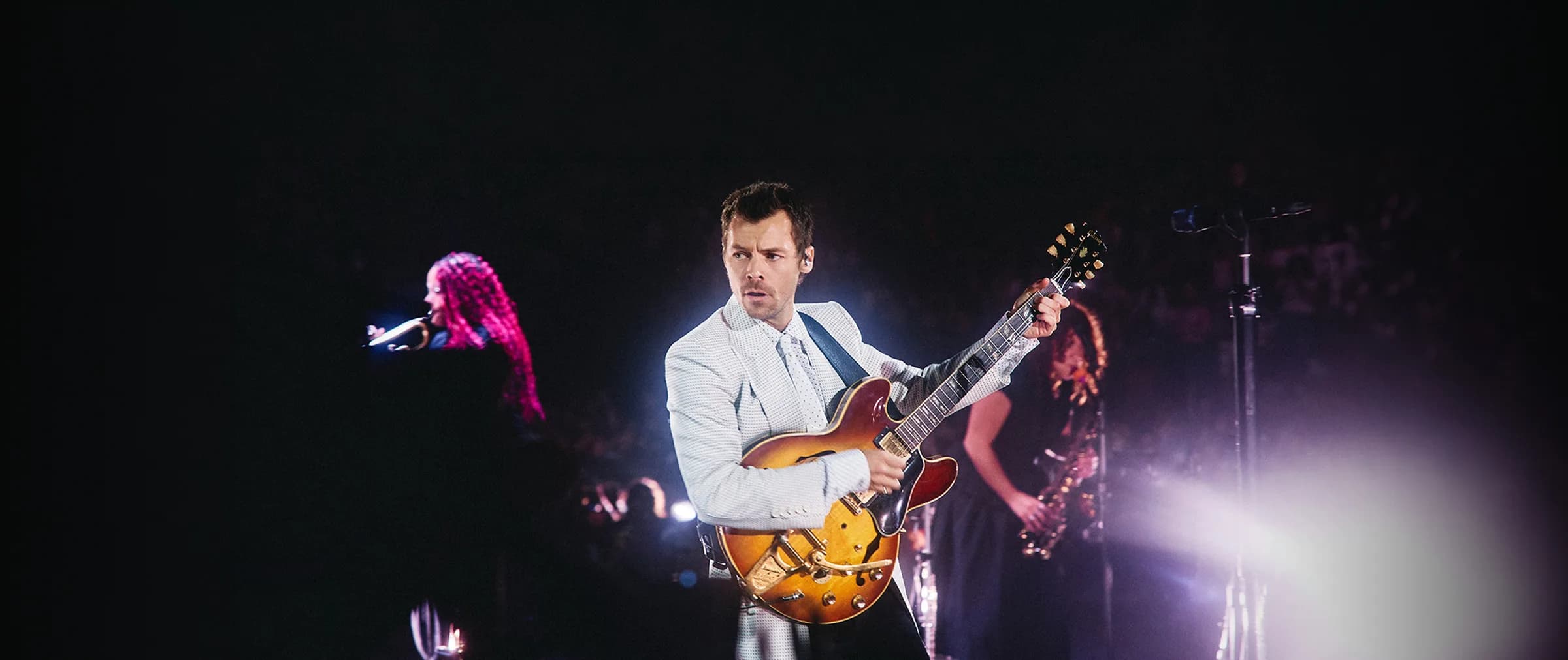 Harry Styles on stage with a guitar — official artist photo